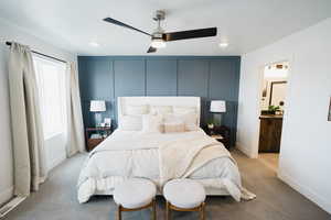 Bedroom featuring ensuite bath, light carpet, multiple windows, and ceiling fan