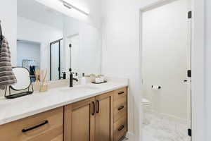 Bathroom featuring vanity, toilet, and a shower with shower door