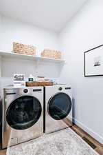 Laundry area with washer and dryer and wood-type flooring