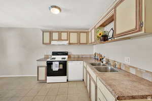 Kitchen featuring light tile patterned flooring, a textured ceiling, sink, and white appliances