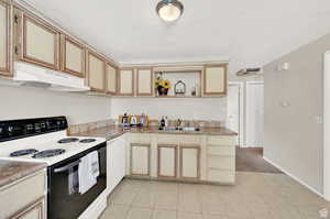 Kitchen with white appliances, light tile patterned floors, exhaust hood, and sink