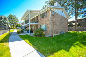 View of property exterior with a lawn and a balcony