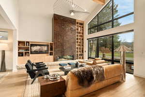 Living room with beamed ceiling, light hardwood / wood-style flooring, high vaulted ceiling, and a fireplace