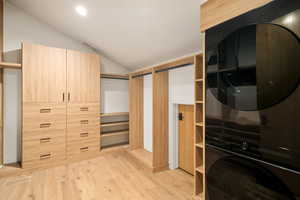 Walk in closet featuring vaulted ceiling and light hardwood / wood-style floors