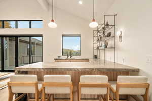 Kitchen featuring wood-type flooring, sink, a kitchen bar, kitchen peninsula, and high vaulted ceiling