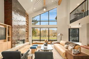 Living room featuring a fireplace, high vaulted ceiling, and plenty of natural light