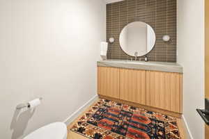 Bathroom featuring toilet, hardwood / wood-style flooring, vanity, and tasteful backsplash