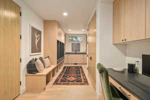 Mudroom with built in desk, sink, and light hardwood / wood-style floors