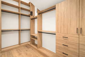 Walk in closet with light wood-type flooring