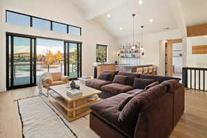 Living room with light hardwood / wood-style flooring, beam ceiling, and high vaulted ceiling