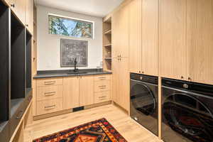 Clothes washing area featuring cabinets, light hardwood / wood-style flooring, sink, and washing machine and clothes dryer