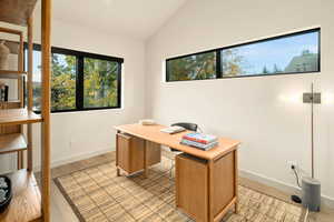 Office with light hardwood / wood-style flooring and lofted ceiling