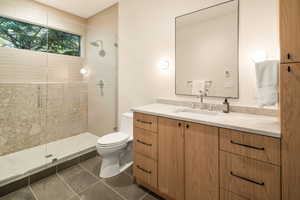 Bathroom with toilet, an enclosed shower, vanity, and tile patterned floors