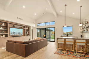 Living room featuring indoor wet bar, beamed ceiling, high vaulted ceiling, and light wood-type flooring