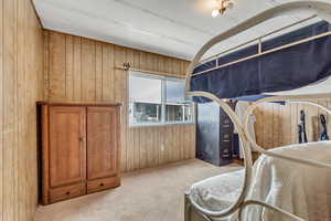 Bedroom featuring wood walls and light colored carpet