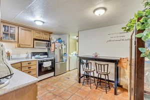 Kitchen featuring light tile patterned flooring, washer / clothes dryer, stainless steel appliances, and light brown cabinetry