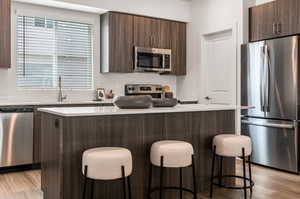 Kitchen with stainless steel appliances, a breakfast bar, light wood-type flooring, and a kitchen island