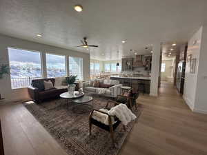 Living room with ceiling fan, light hardwood / wood-style flooring, and a textured ceiling