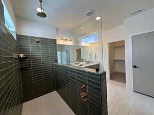 Bathroom featuring tiled shower, vanity, and a textured ceiling