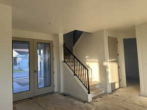 Foyer entrance with french doors, light hardwood / wood-style flooring, and a textured ceiling