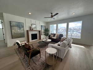 Living room featuring a textured ceiling, light hardwood / wood-style flooring, and ceiling fan