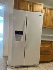 Kitchen featuring light tile patterned flooring and white refrigerator with ice dispenser