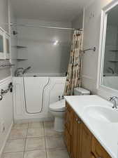 Full bathroom with vanity, shower / bath combo with shower curtain, toilet, and tile patterned flooring