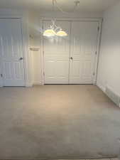 Empty room featuring a chandelier and light carpet