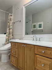 Bathroom with vanity, toilet, a shower with shower curtain, and tile patterned flooring