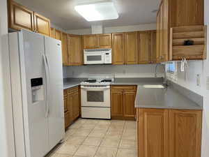 Kitchen featuring sink, white appliances, and light tile patterned floors