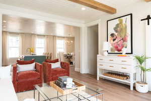 Living room with an inviting chandelier, light hardwood / wood-style flooring, a barn door, and beamed ceiling