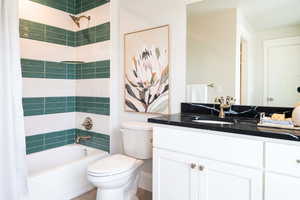 Full bathroom featuring vanity, toilet, and shower / bathtub combination with curtain