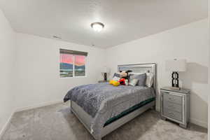 Bedroom with light carpet and a textured ceiling