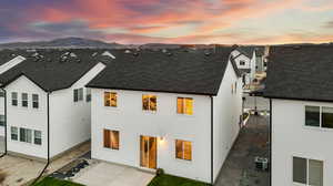 Back house at dusk with a mountain view, a patio, and central AC unit