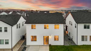 Back house at dusk featuring a patio area and central AC unit