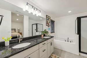 Bathroom featuring vanity, a textured ceiling, tile patterned flooring, and plus walk in shower