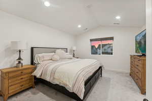 Bedroom featuring light carpet and lofted ceiling