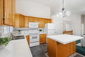 Kitchen featuring tile counters, sink, a center island, pendant lighting, and white appliances