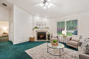 Carpeted living room with ceiling fan and lofted ceiling