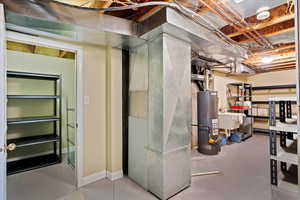 Utility room with sink, gas water heater, and heating unit