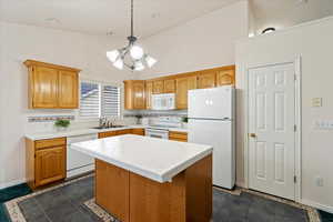 Kitchen featuring a kitchen island, sink, tile counters, decorative light fixtures, and white appliances