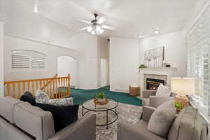 Living room featuring carpet flooring, a premium fireplace, lofted ceiling, and ceiling fan