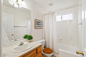 Full bathroom featuring toilet, shower / bath combo with shower curtain, and vanity