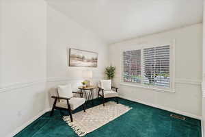 Sitting room with dark carpet and lofted ceiling