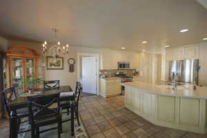 Kitchen featuring tasteful backsplash, sink, stainless steel appliances, pendant lighting, and a chandelier