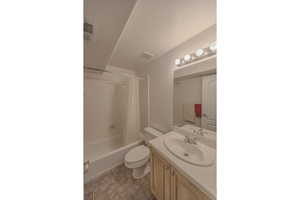 Full basement bathroom featuring vanity, toilet, tile patterned floors, and shower / bath combination with curtain