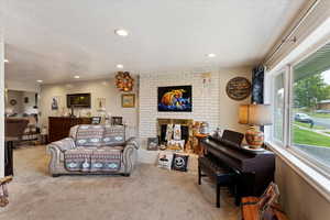 Carpeted living room featuring a wealth of natural light, a fireplace, and a textured ceiling