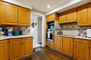 Kitchen featuring dark wood-type flooring, appliances with stainless steel finishes, and decorative backsplash