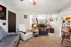 Living room with light carpet, a textured ceiling, and ceiling fan