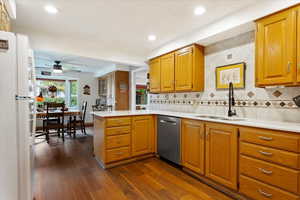 Kitchen with kitchen peninsula, dishwasher, dark hardwood / wood-style floors, sink, and white refrigerator